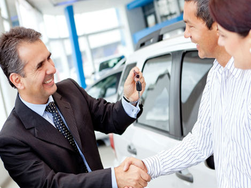 picture of car dealer handing keys to man and woman