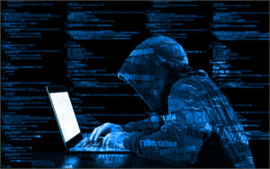 Hooded man hacking into a computer.