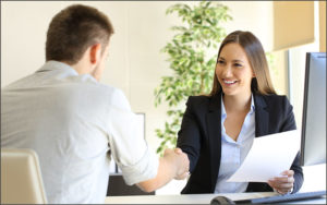Woman at desk shaking hands with man