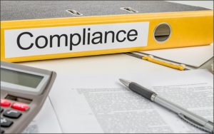 Bind med Compliance label sidder på skrivebord